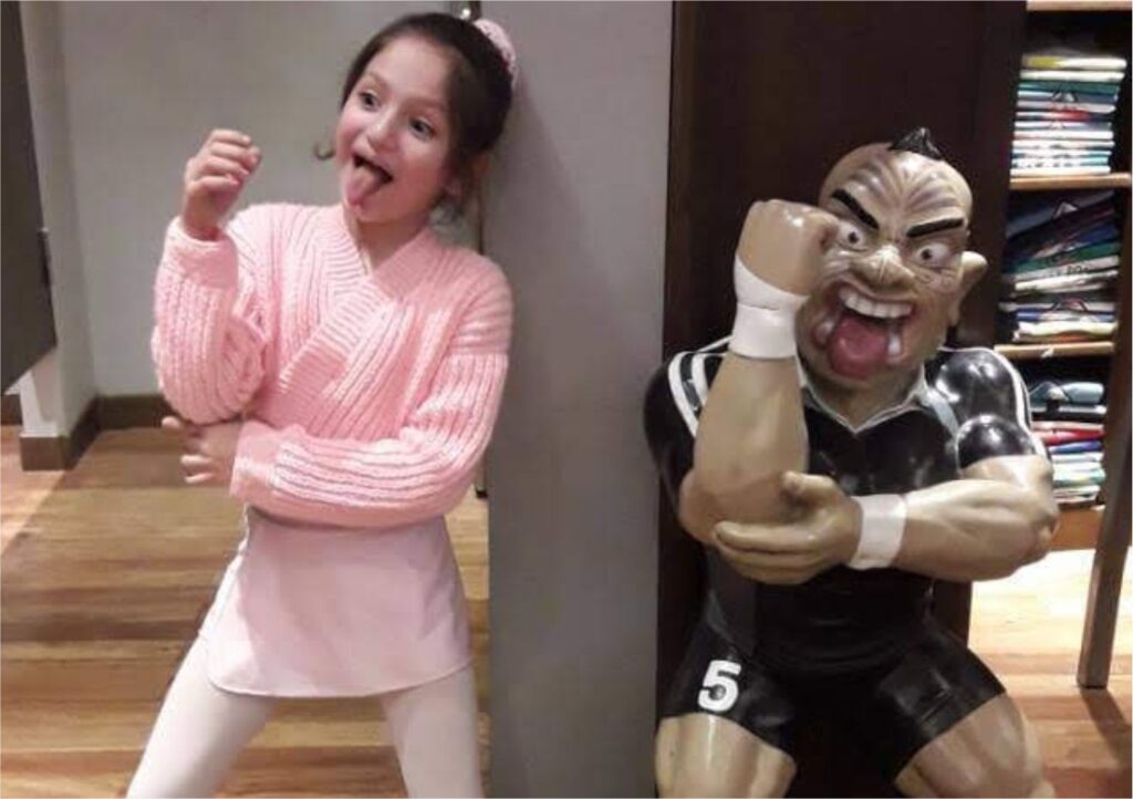 niña imitando muñeco decorativo